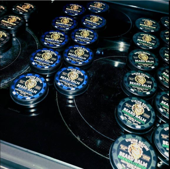 Dozens of Viking Recon beard balm tins cooling on the stovetop — small-batch, made by hand.